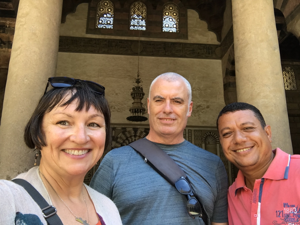 Trois individus posant devant un bâtiment historique.