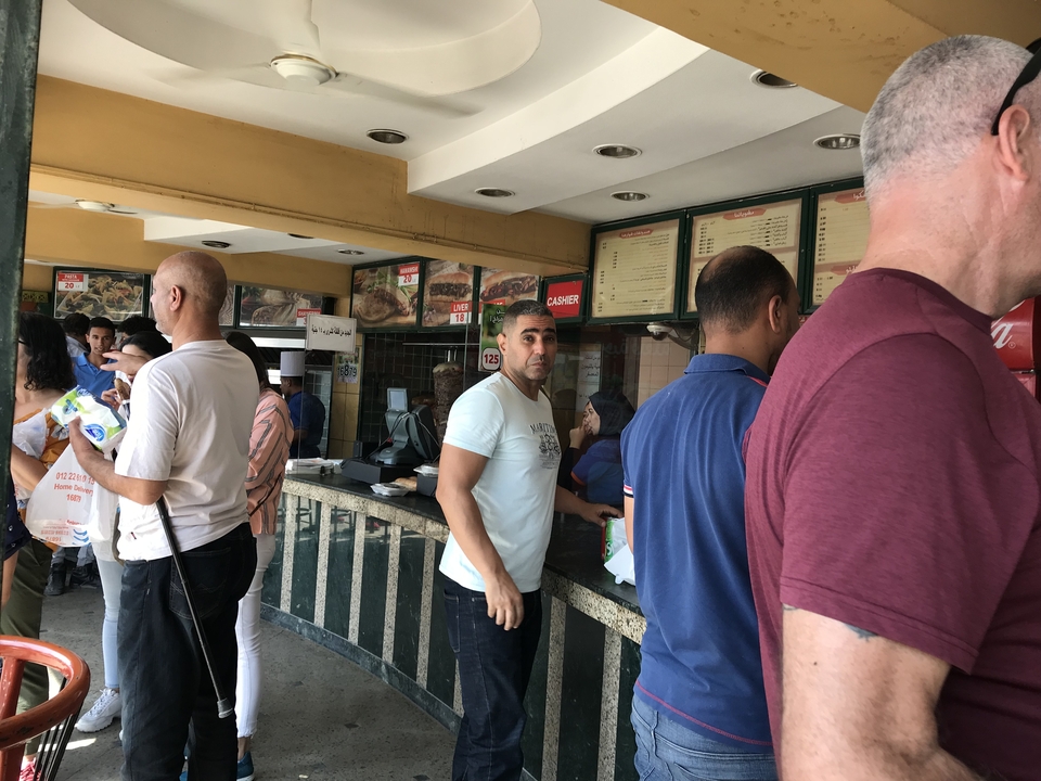 Des gens debout dans une aire de restauration animée.