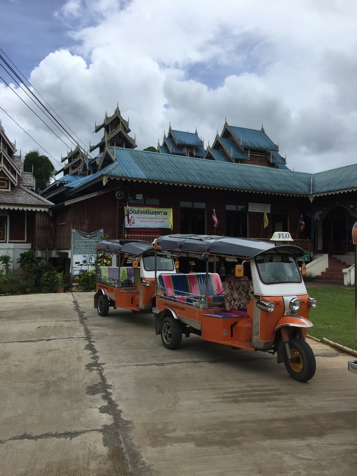 Tuk-tuks garés devant un bâtiment de style thaïlandais.