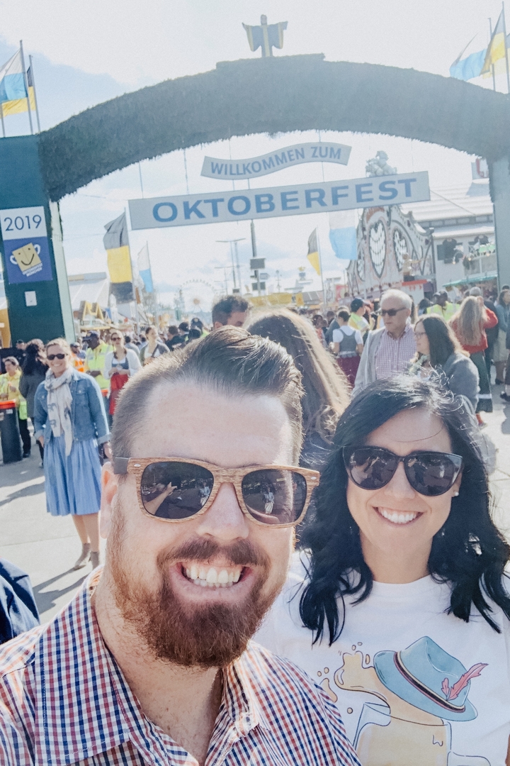 Un couple portant des lunettes de soleil, au milieu d'une scène de fête de rue animée.