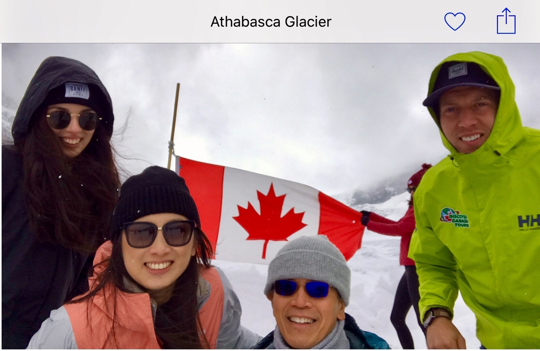 Groupe de personnes tenant un drapeau canadien dans un paysage enneigé.