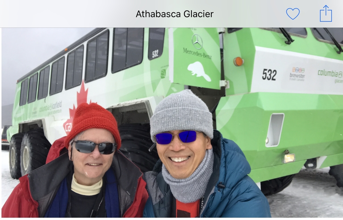 Deux personnes posant devant un gros véhicule des neiges.