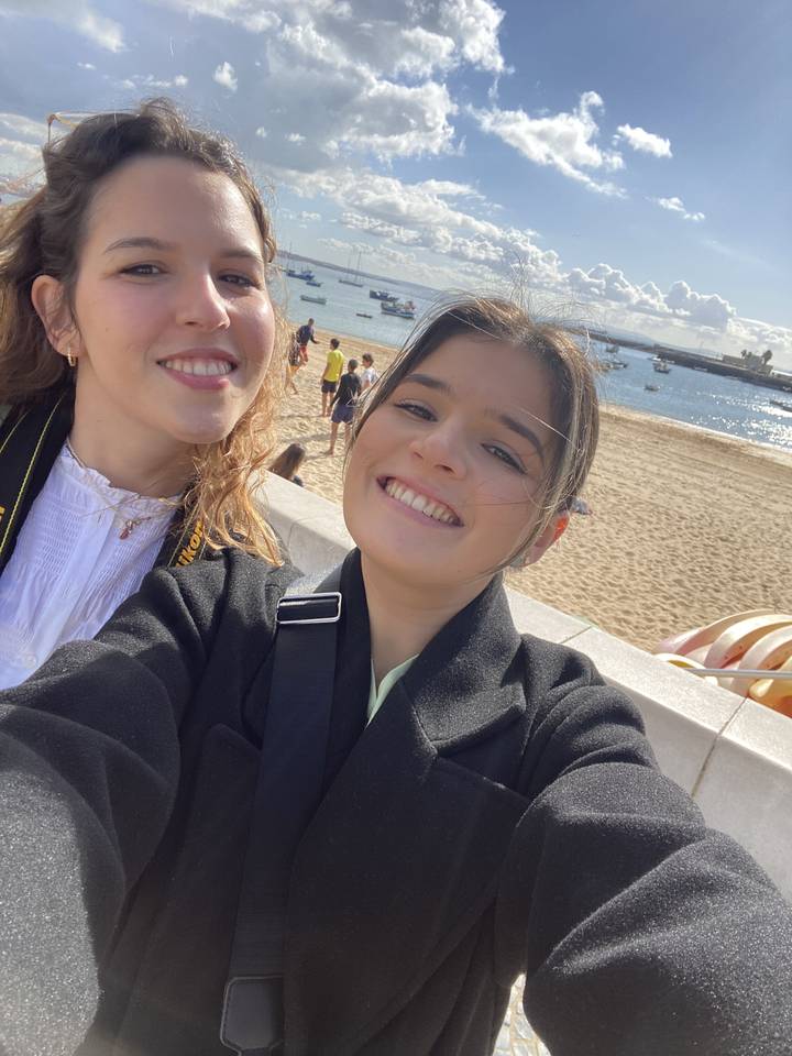 Deux personnes prenant un selfie sur une plage avec un ciel lumineux.