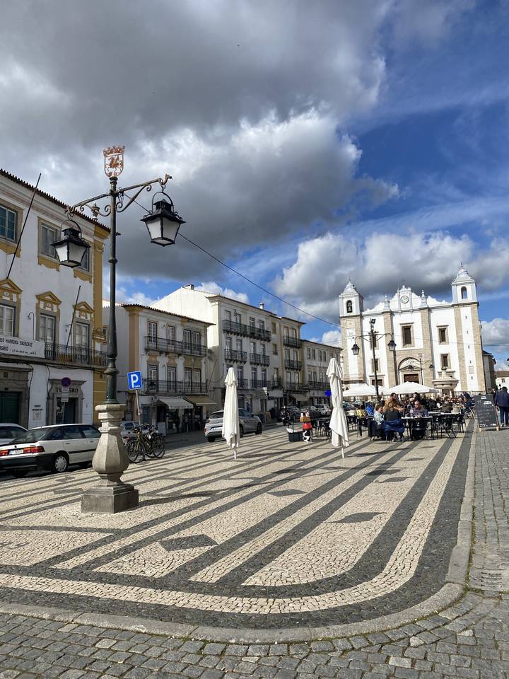Place de ville avec bâtiments historiques et ciel nuageux.