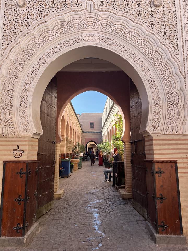 People walking through an archway in a traditional setting.