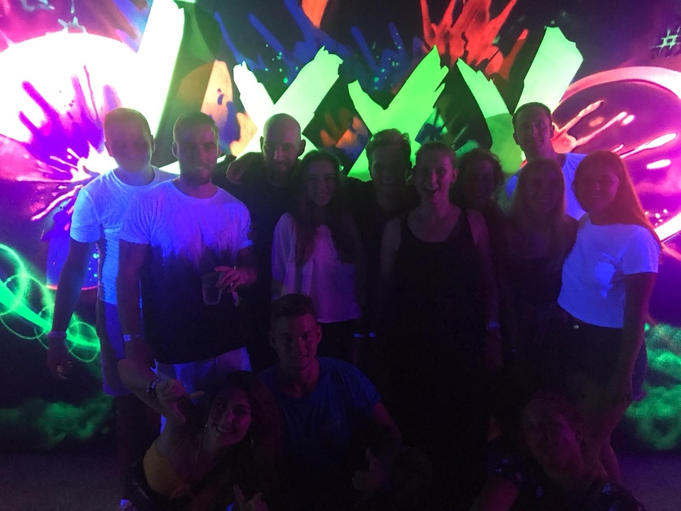 Groupe de personnes à une fête sombre avec des lumières colorées.