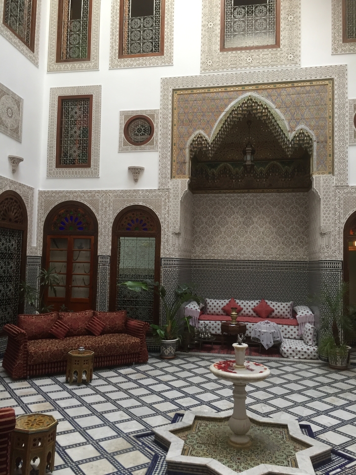 An outdoor courtyard with intricate tile work and decorative arches, featuring comfortable seating.