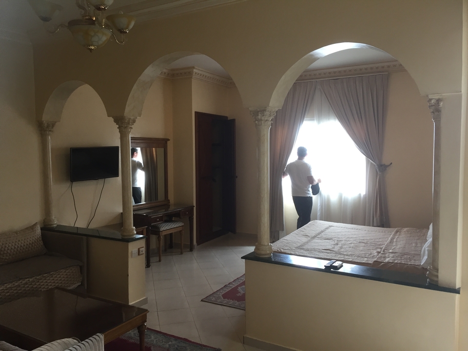 Une personne regardant par la fenêtre dans une pièce avec des arcs et une décoration marocaine traditionnelle.