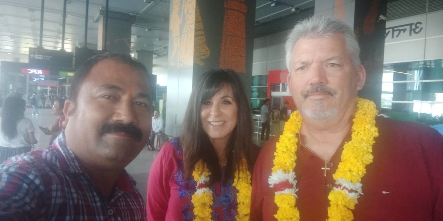 Trois personnes souriant ensemble dans ce qui semble être un terminal d'aéroport.