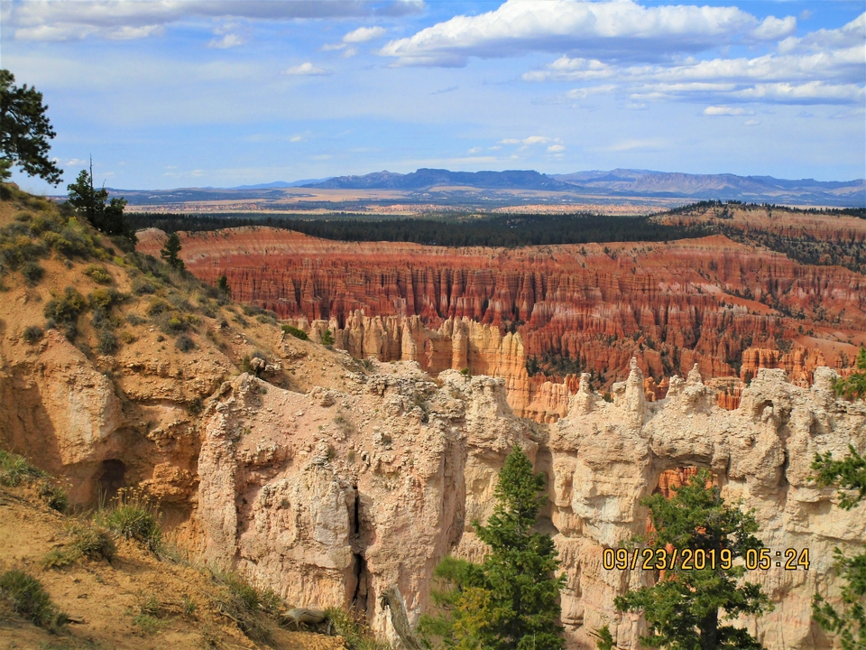 Vue panoramique du canyon de Bryce avec ses formations rocheuses distinctives et les montagnes au loin.