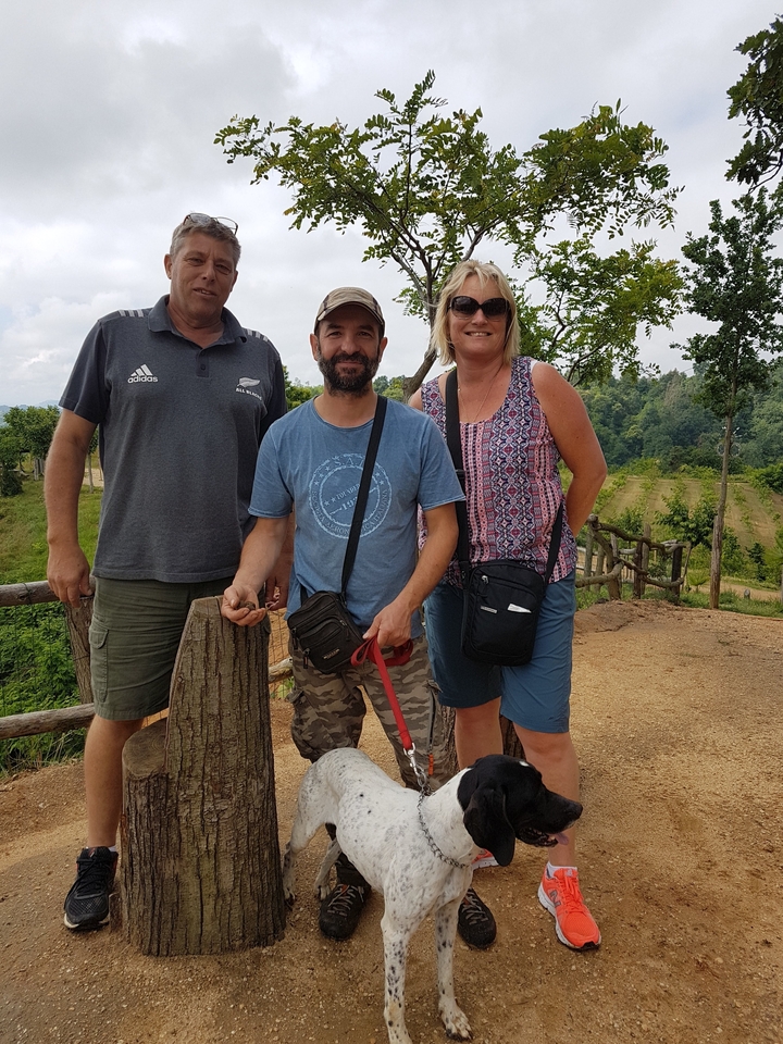 Trois personnes posant en extérieur avec un décor pittoresque en arrière-plan.