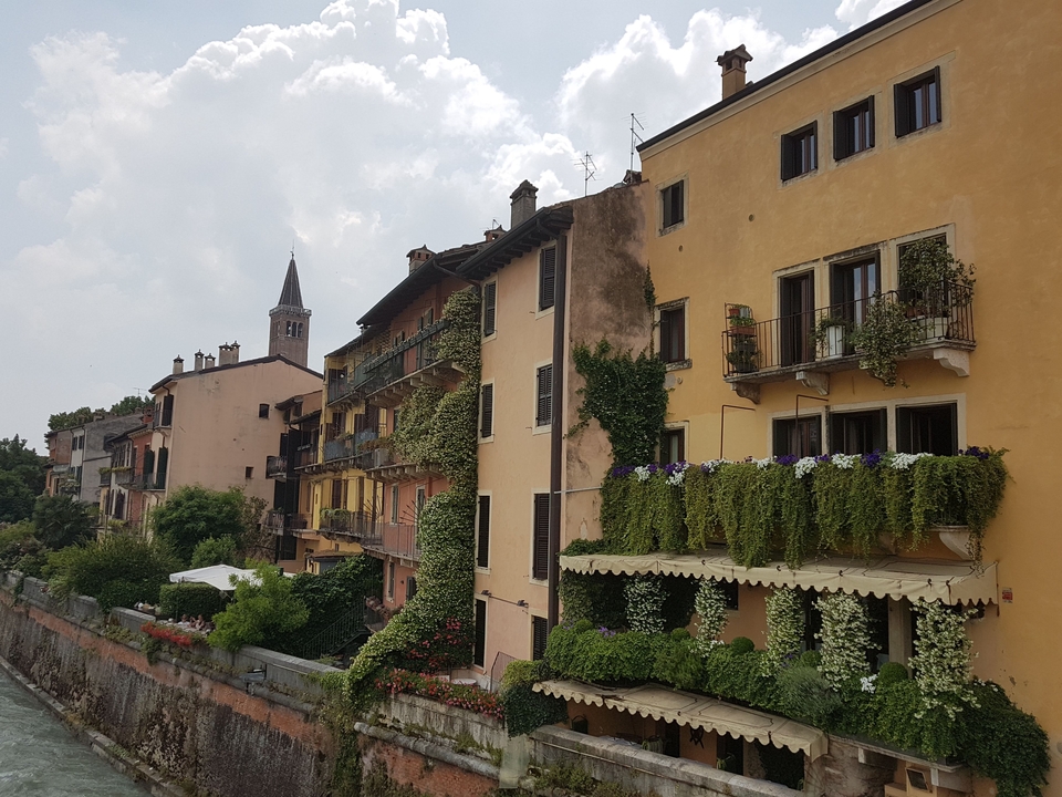Bâtiments colorés avec des plantes et un clocher d'église en arrière-plan.