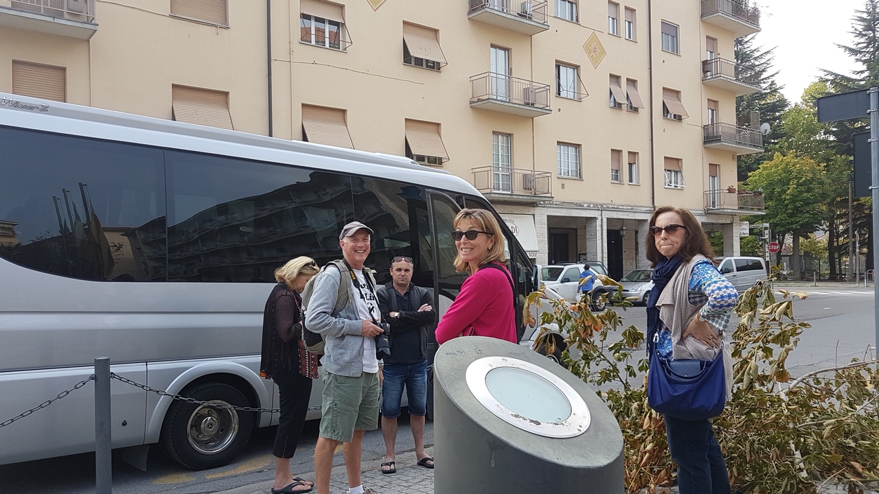 Groupe de personnes debout près d'un autocar de tourisme dans une rue de la ville.
