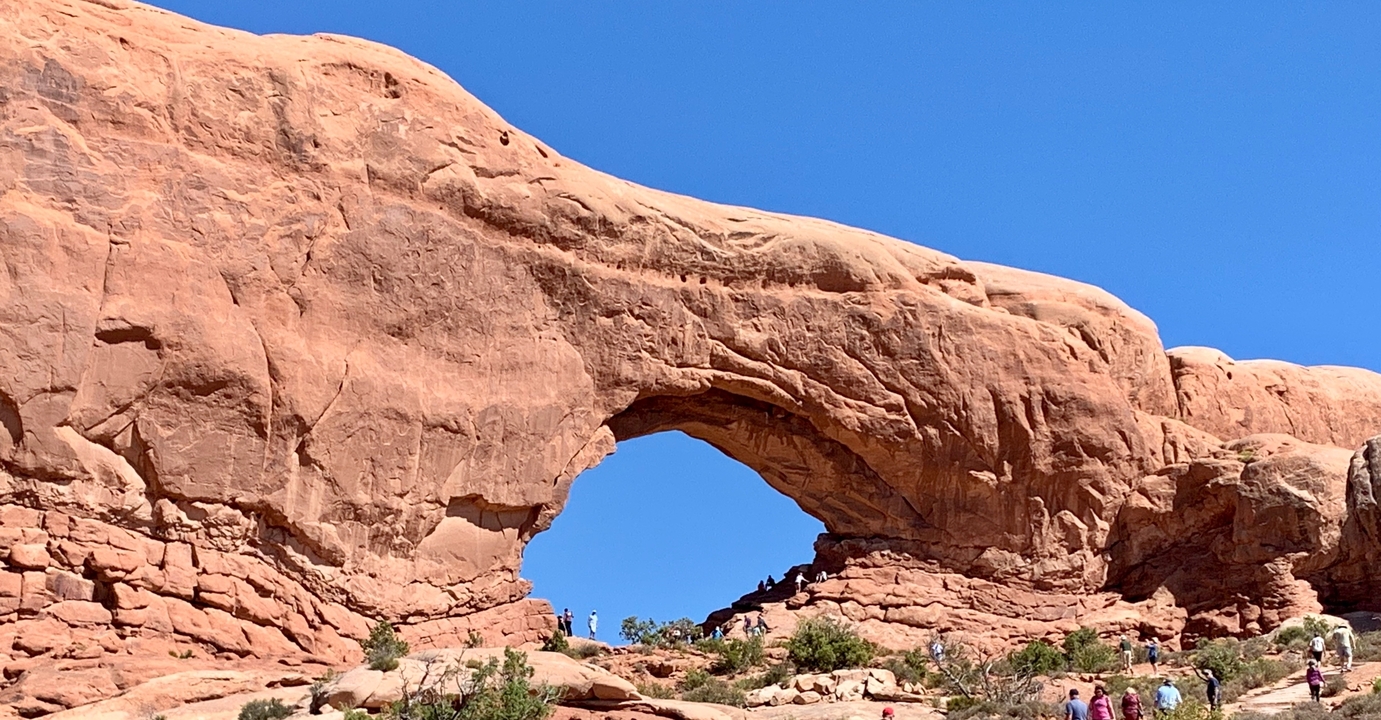 Arche rocheuse naturelle avec des personnes autour, partie du parc national des Arches.