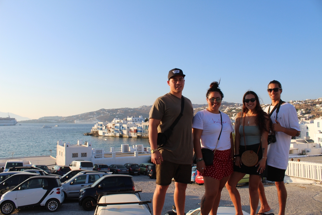 A group of people posing with a seaside town in the background.