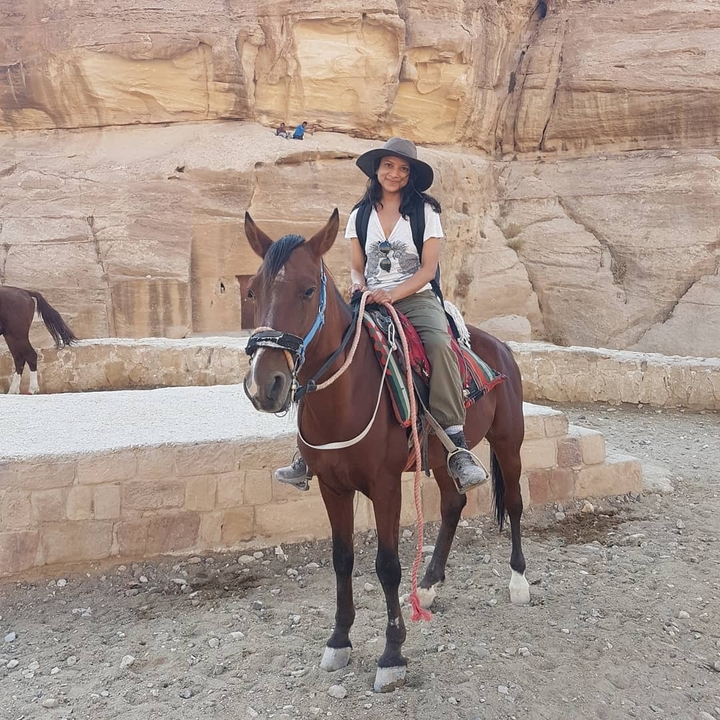 Person on horseback in a stone structure environment.