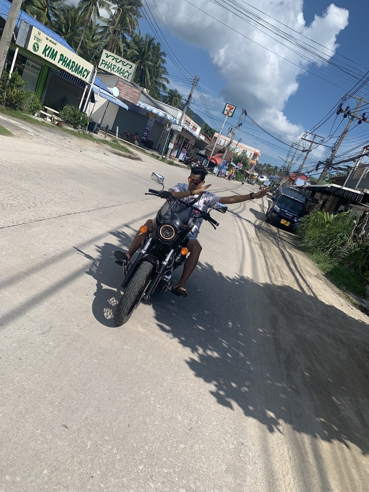 Homme posant sur une moto dans une rue dans un endroit chaud.