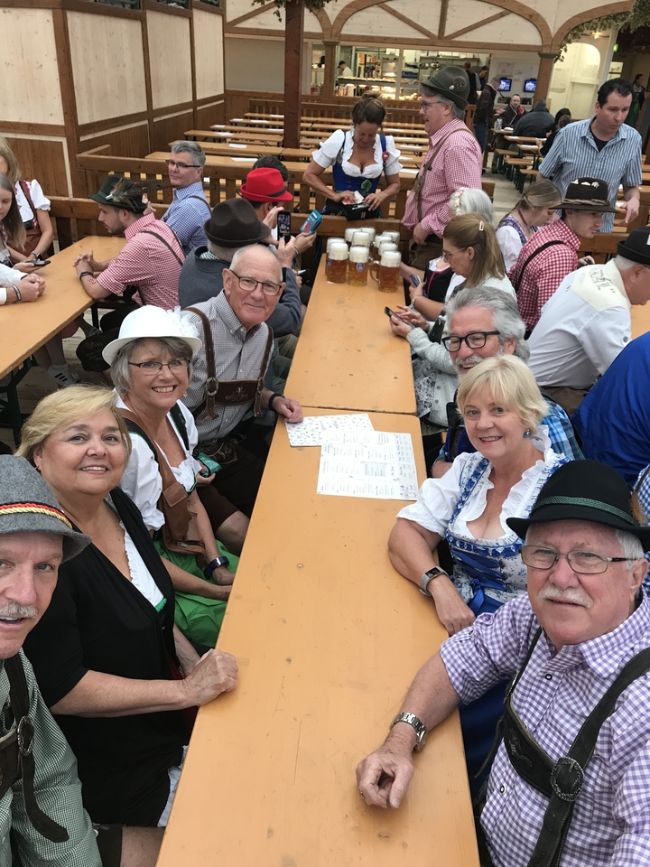 Groupe de personnes assises à une table de brasserie en plein air, savourant leurs boissons.