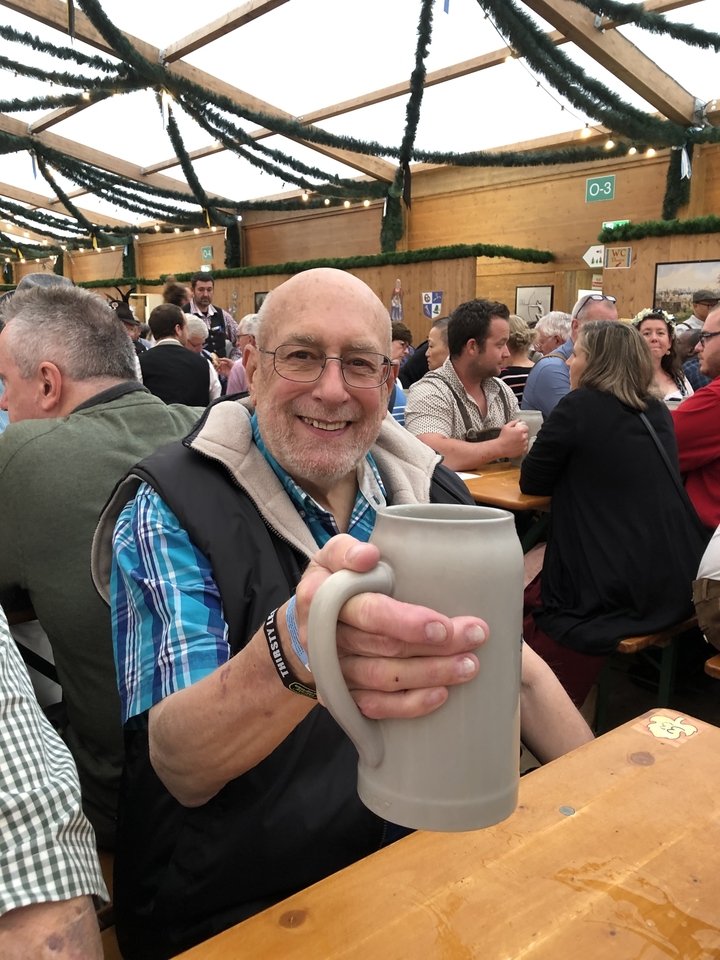 Homme tenant une chope de bière dans une tente de festival.