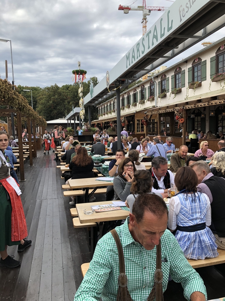 Jardin à bière en plein air avec des personnes qui dînent portant des vêtements traditionnels.
