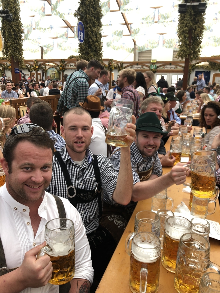 Groupe d'hommes levant des chopes de bière dans une atmosphère festive.