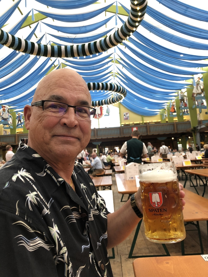 Un homme tenant une chope de bière dans une grande tente.