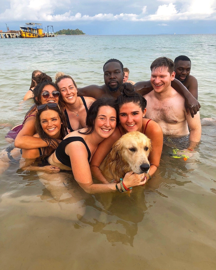 Groupe de personnes et un chien dans l'eau.