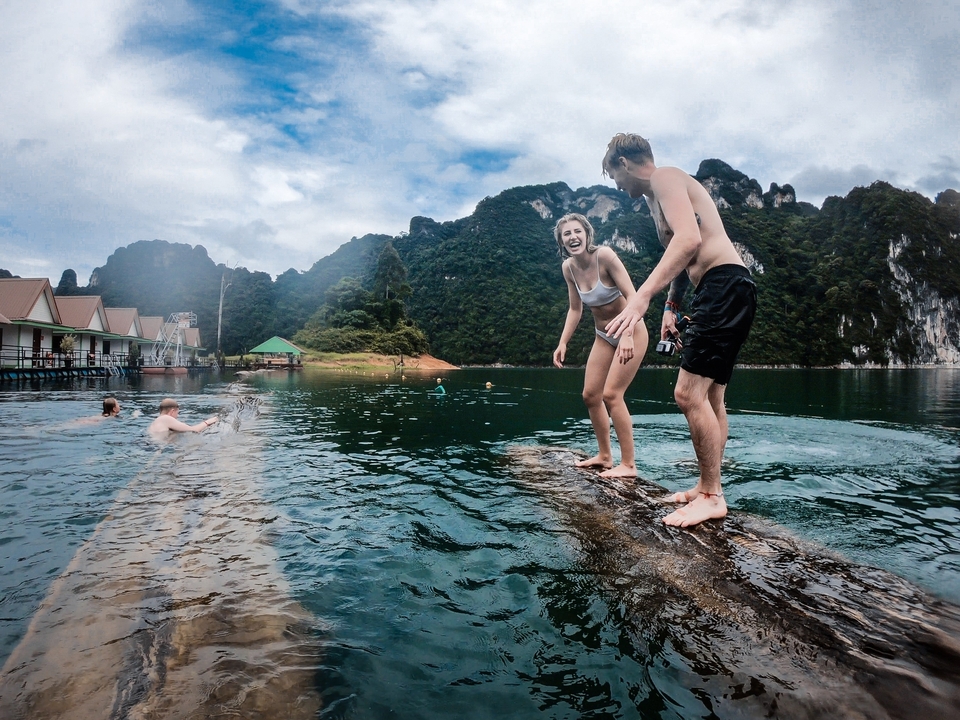 People having fun in the water on a floating log.