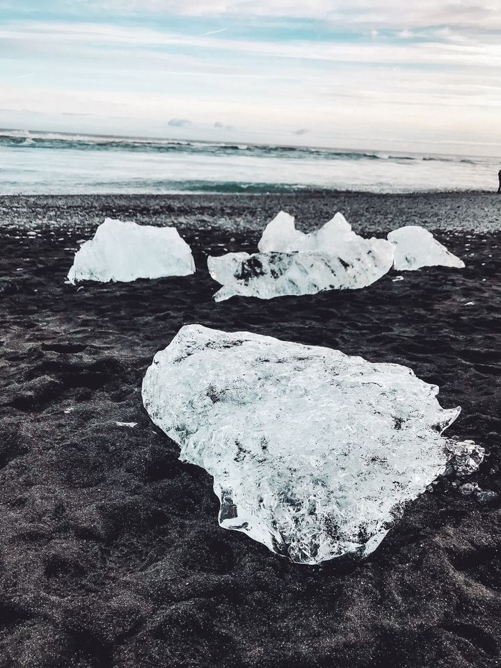 Plage de sable noir avec des morceaux de glace.