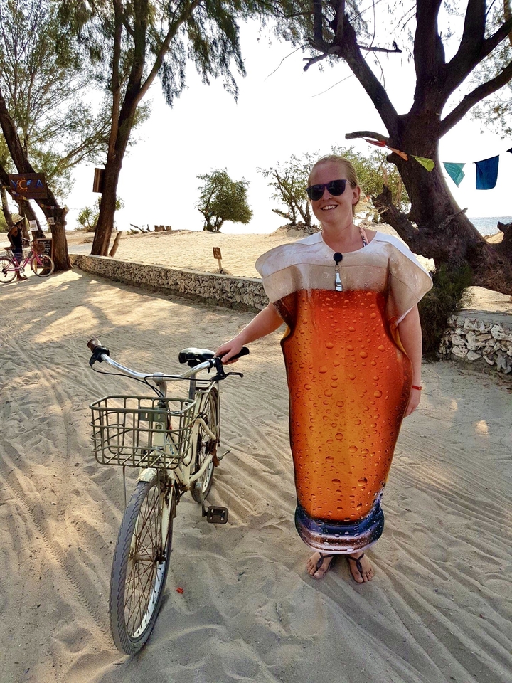 Personne déguisée en bière tenant un vélo.