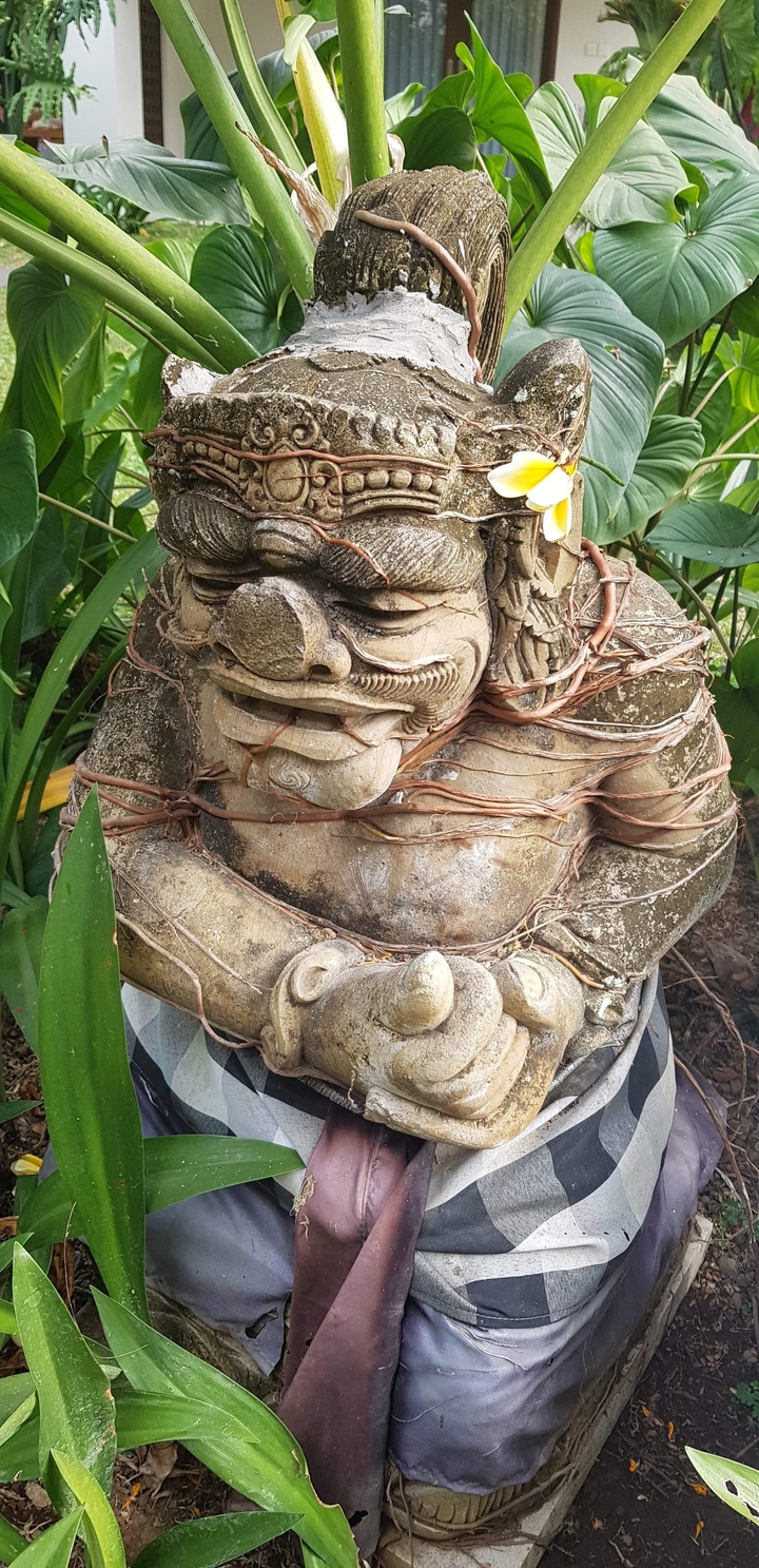 Sculpture en pierre entourée de plantes.