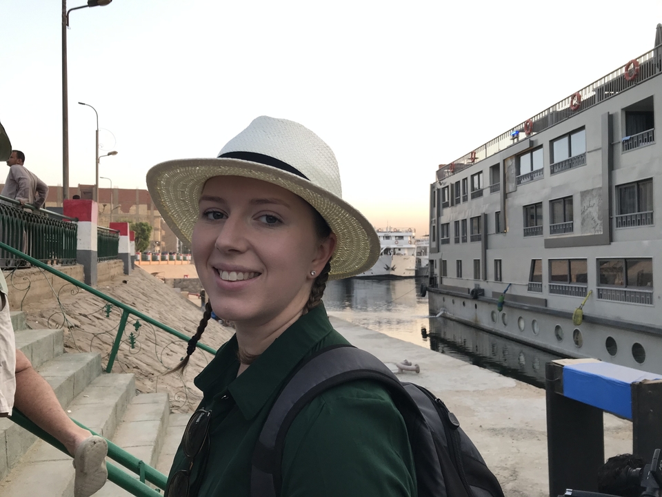 Personne souriante devant un navire de croisière à quai.