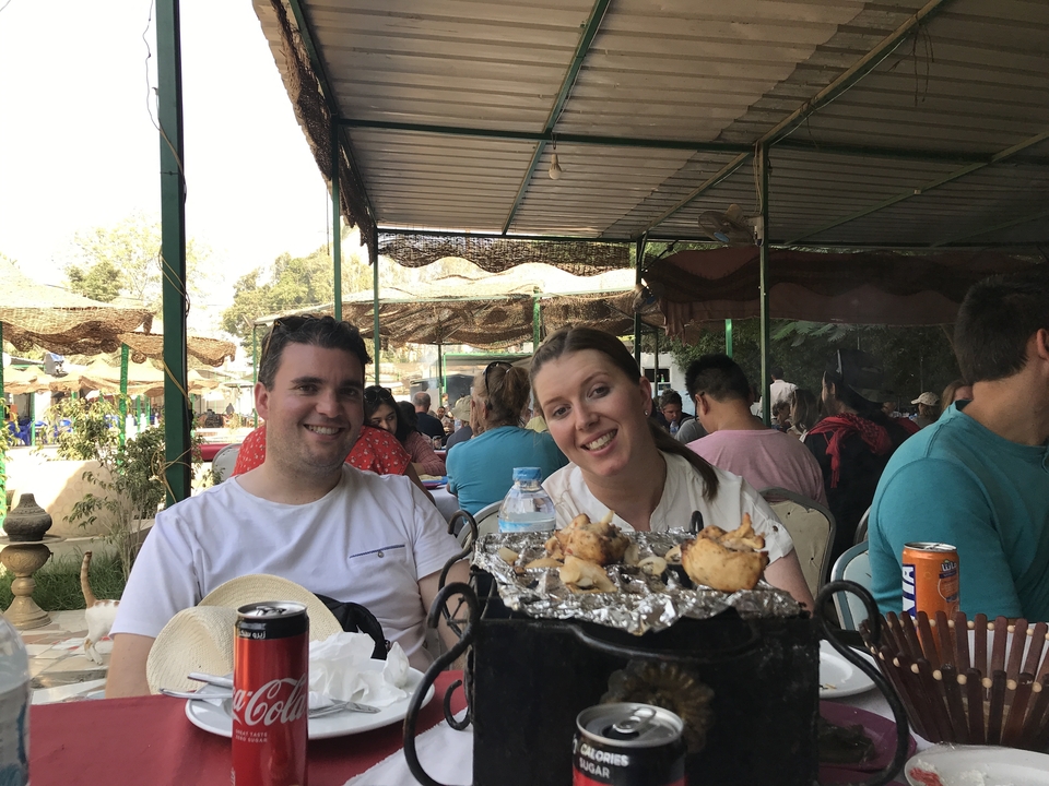Couple dînant en plein air avec un restaurant animé en arrière-plan.