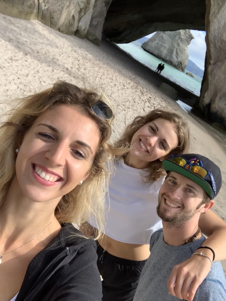Trois personnes souriant à la caméra sur une plage.