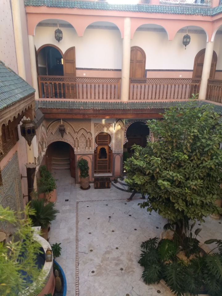 Traditional Moroccan courtyard with decorative arches and a tree.
