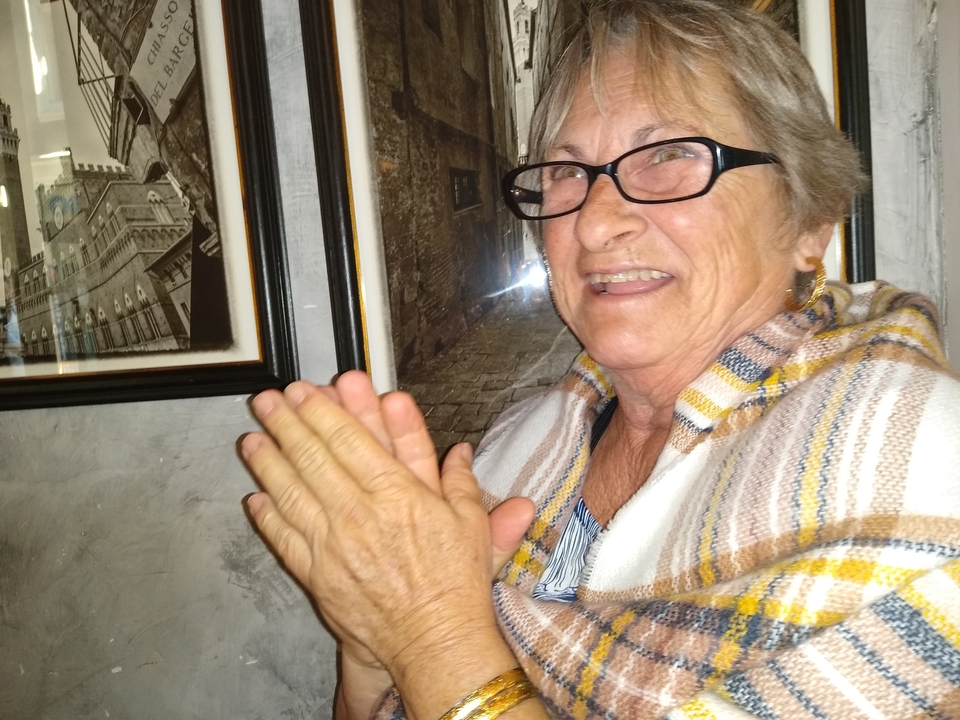 Femme âgée à l'intérieur avec des photographies encadrées au mur.
