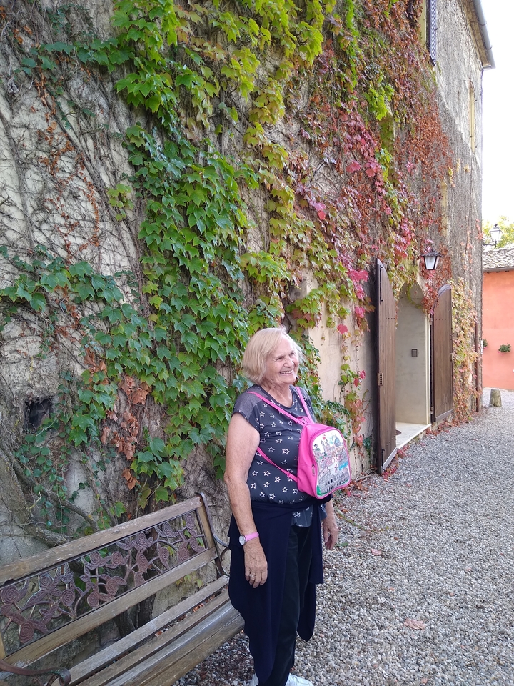 Femme souriante devant un mur couvert de lierre.