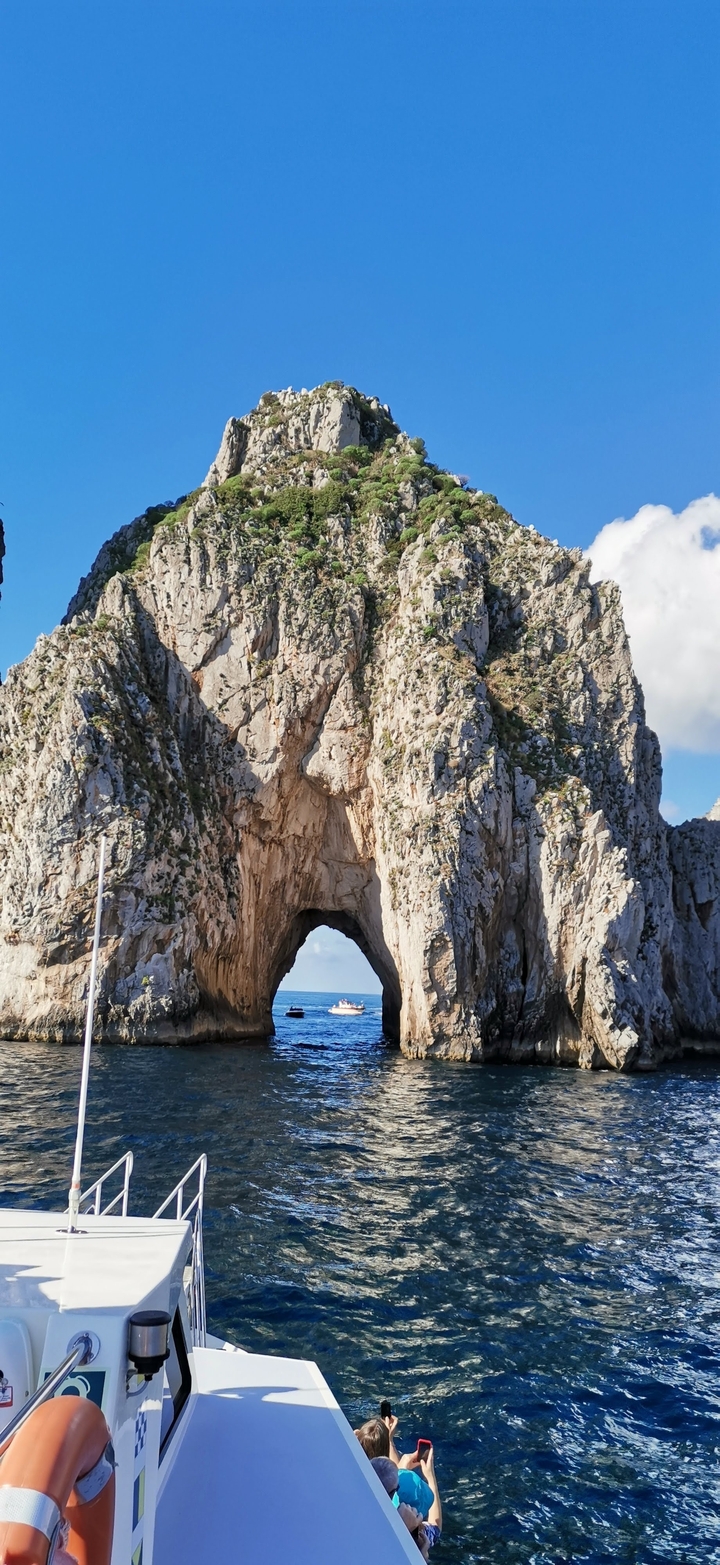 Grande formation d'arche naturelle en roche contre un ciel bleu.