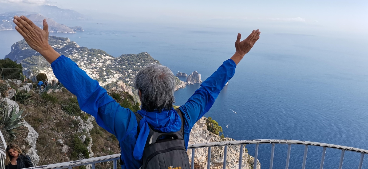 Personne les bras levés profitant d'une vue côtière depuis un point de vue élevé.