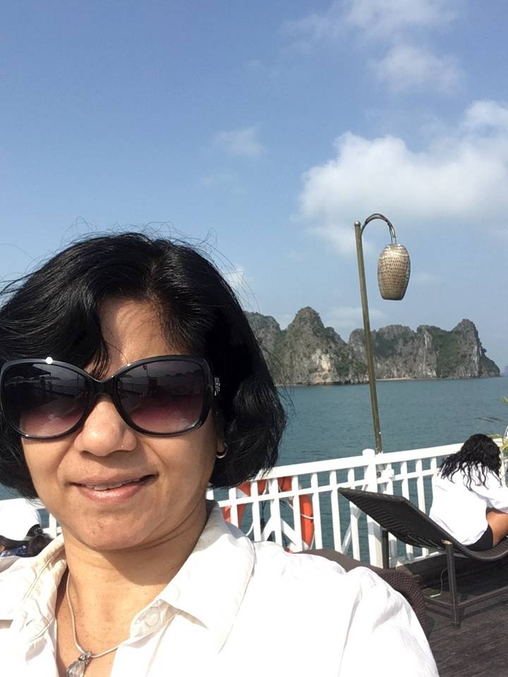 Personne en lunettes de soleil sur un bateau avec un arrière-plan rocheux.