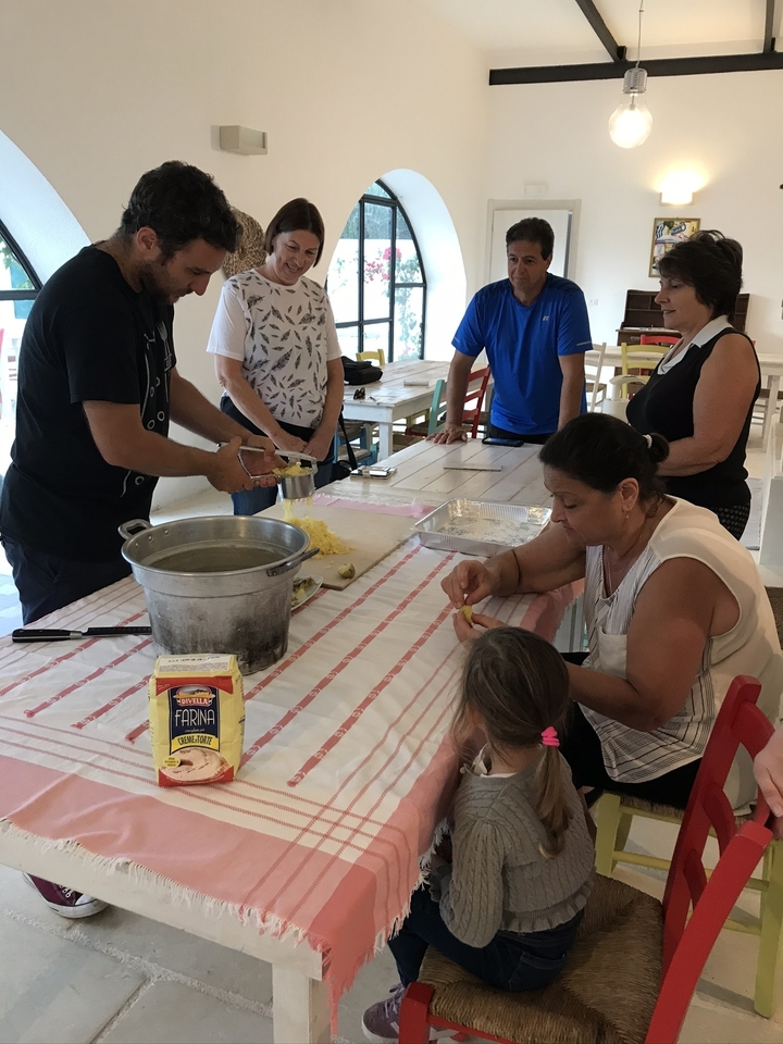 Un groupe participant à un cours de fabrication de pâtes à une table à l'intérieur