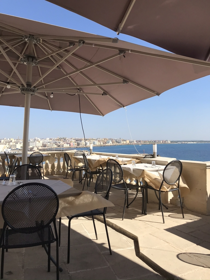 Une terrasse de restaurant avec vue sur une ville côtière et la mer