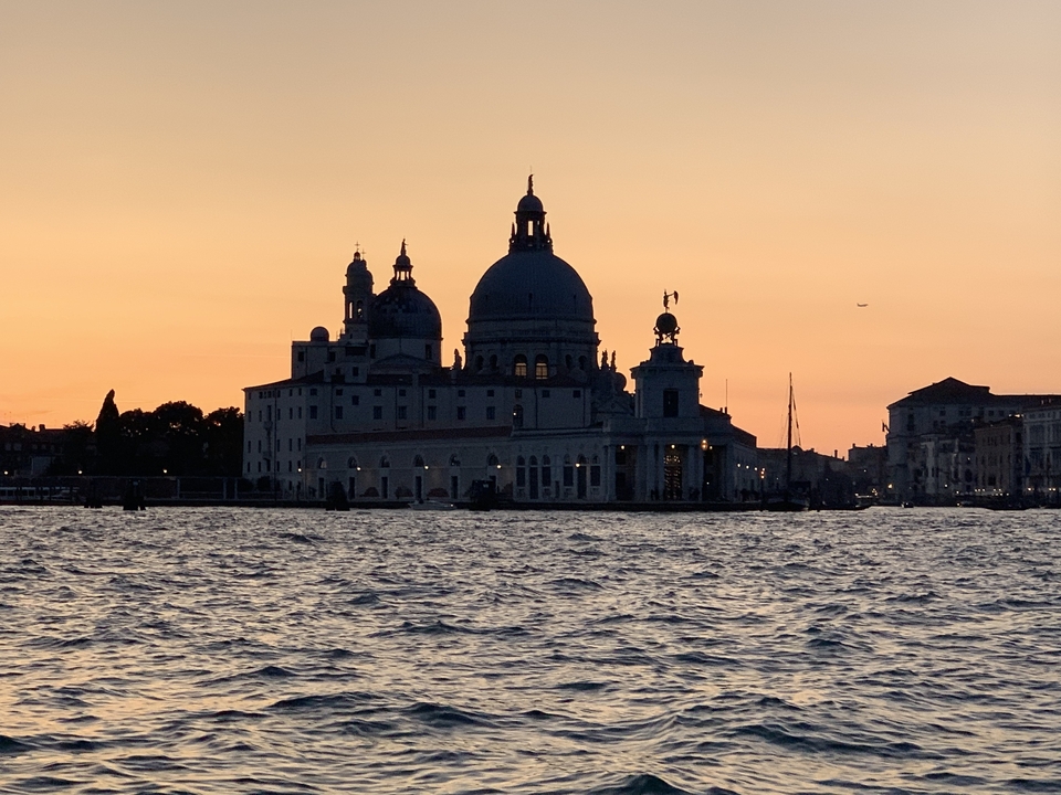Silhouette d'un bâtiment se détachant sur un coucher de soleil au-dessus de l'eau.