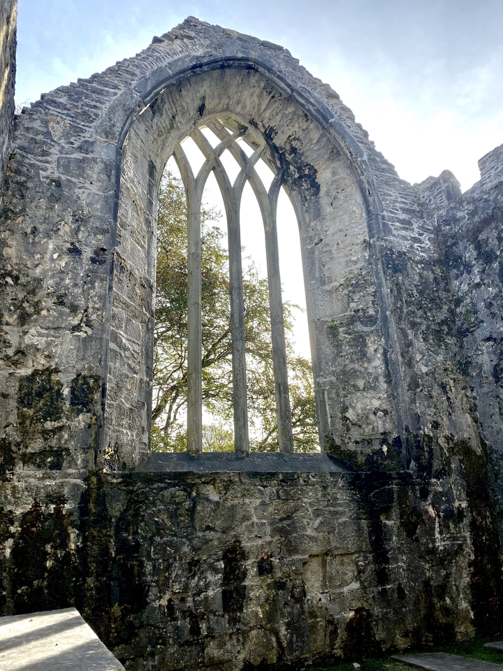 Vieux mur de pierre avec un arbre visible à travers la fenêtre.