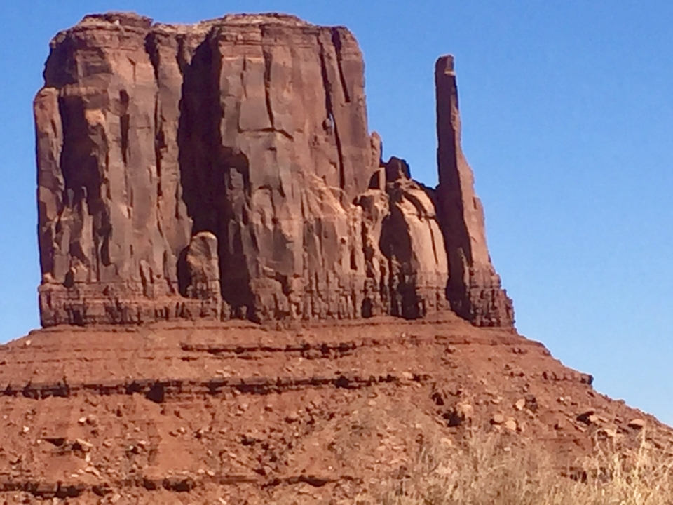 Formations rocheuses de Monument Valley sous un ciel bleu dégagé.