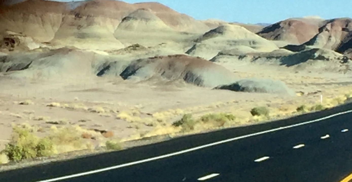 Paysage désertique avec des collines et une route au premier plan.
