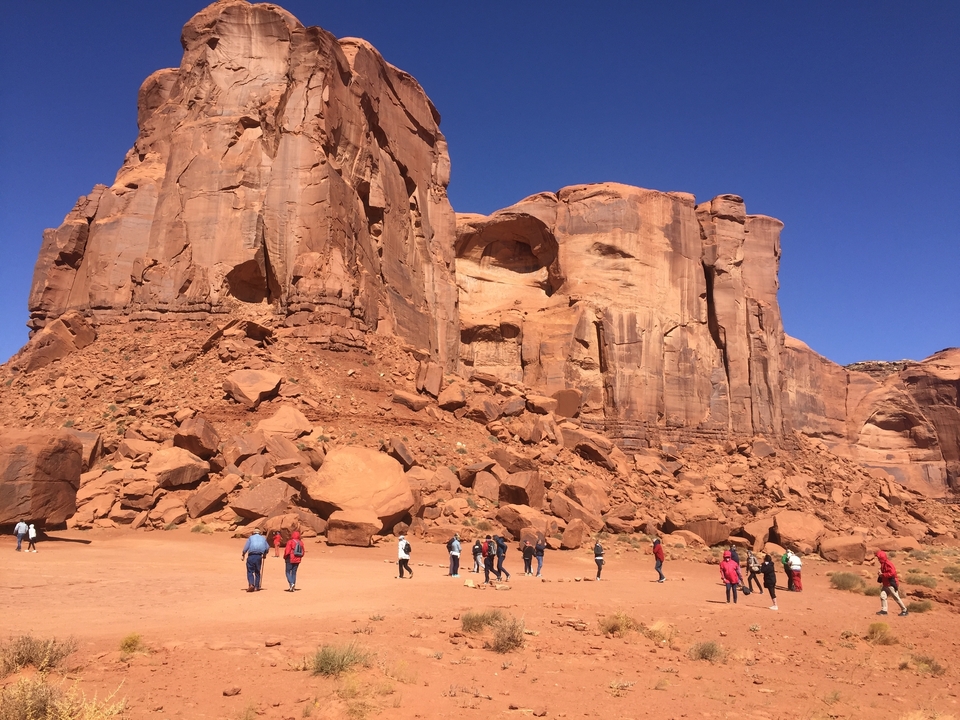 Groupe de personnes marchant près de grandes formations rocheuses.