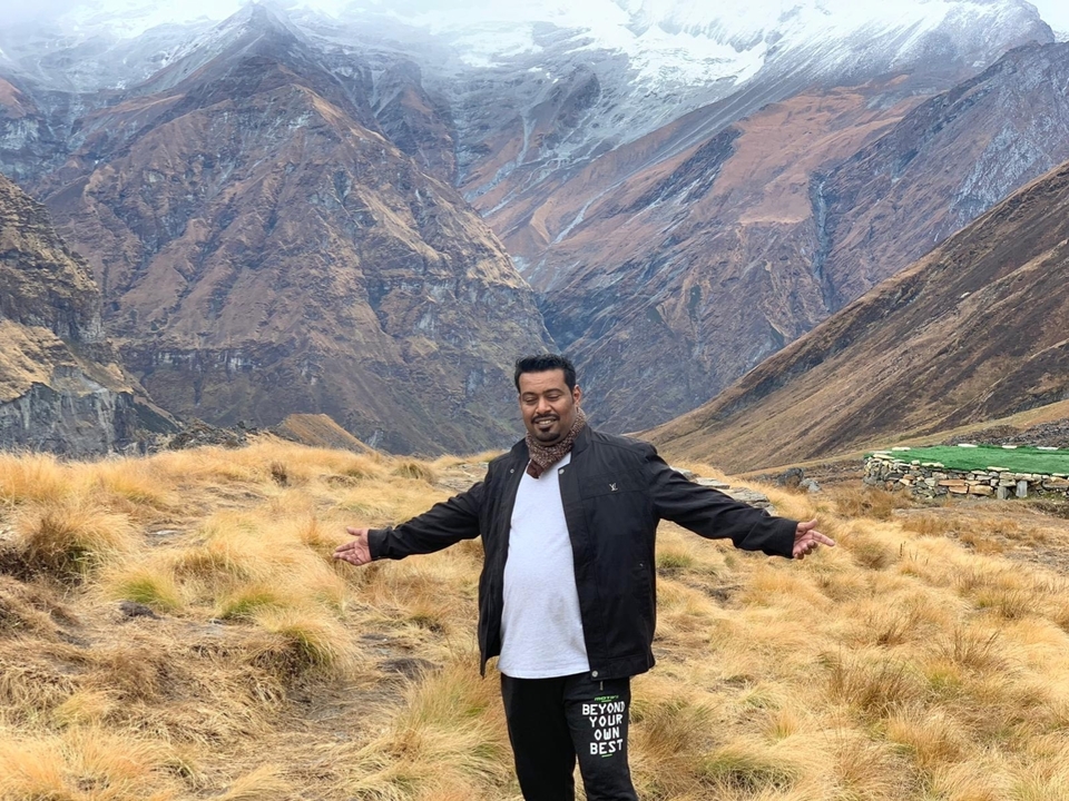 Personne posant les bras étendus dans un paysage montagneux.