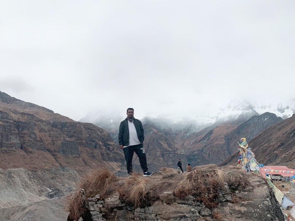 Personne debout sur une montagne avec un paysage enneigé en arrière-plan.