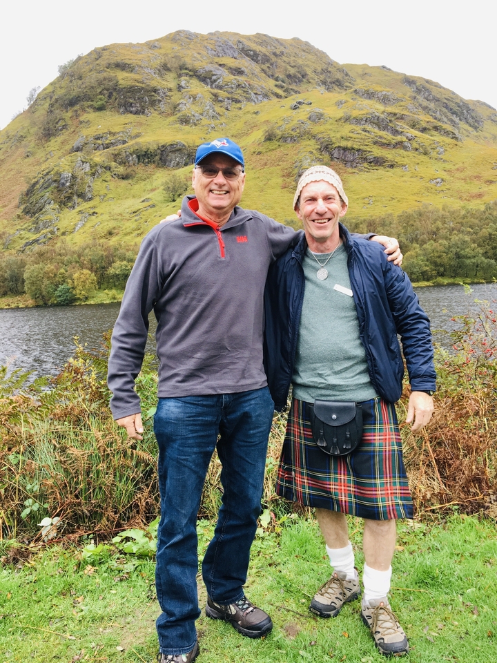 Deux hommes debout près d'un loch dans un cadre champêtre.